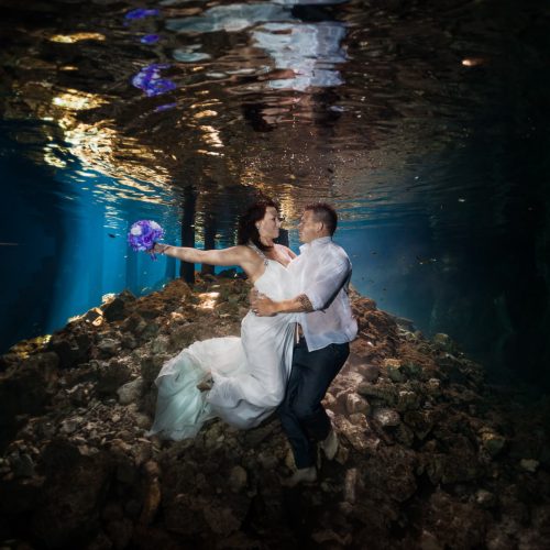 Bride and Groom holding each other in underwater trash the dress in Mayan Cenote at Riviera Maya