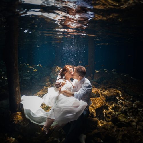 Bride and Groom kissing in underwater trash the dress in Mayan Cenote at Riviera Maya