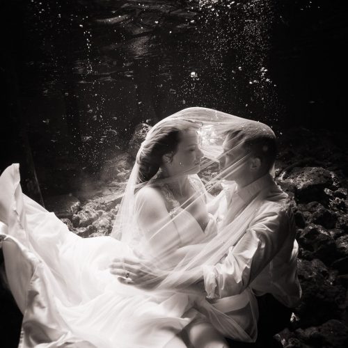 Black and white picture of groom and bride kissing in underwater trash the dress in Mayan Cenote at Riviera Maya