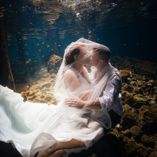 Groom and bride kissing in underwater trash the dress in Mayan Cenote at Riviera Maya
