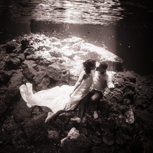 Black and white underwater photography of groom and bride trash the dress in Mayan Cenote at Riviera Maya