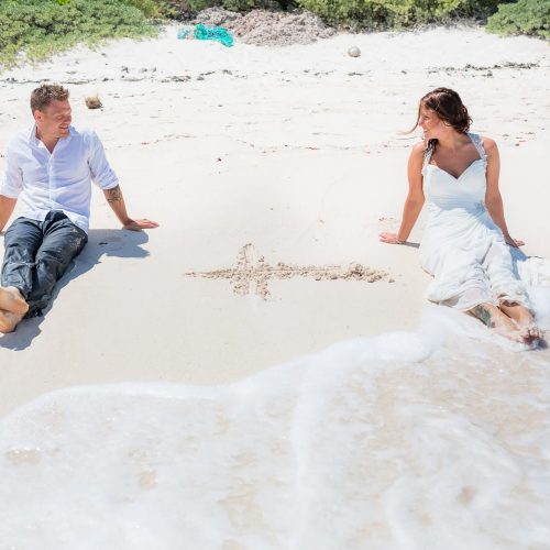 Groom and bride sitting by the shore at trash the dress at Riviera Maya beach