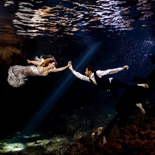Couple holding hands in underwater photo in Maya Cenote