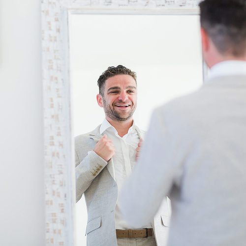 Groom looking at himself in mirror before wedding