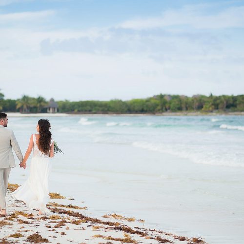 Bride and groom walking away on beach in Riviera Maya