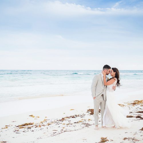 Bride and groom kissing on beach after wedding