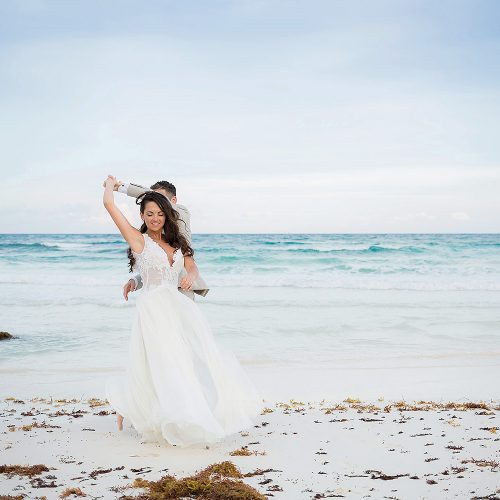 Bride and groom having fun on beach.