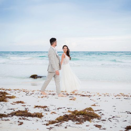 Bride and groom walking on beach in Riviera Maya