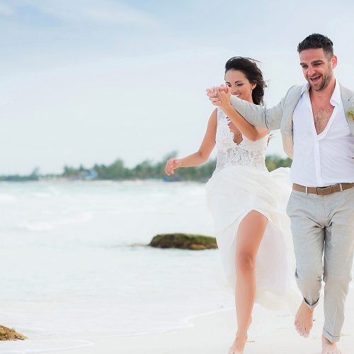 Bride and groom running on beach