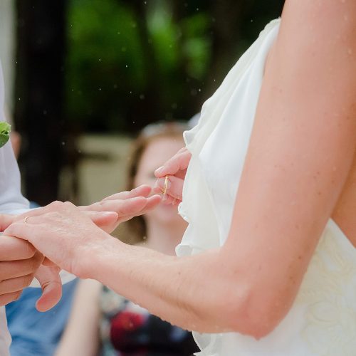Close up of groom putting on ring at wedding ceremony.