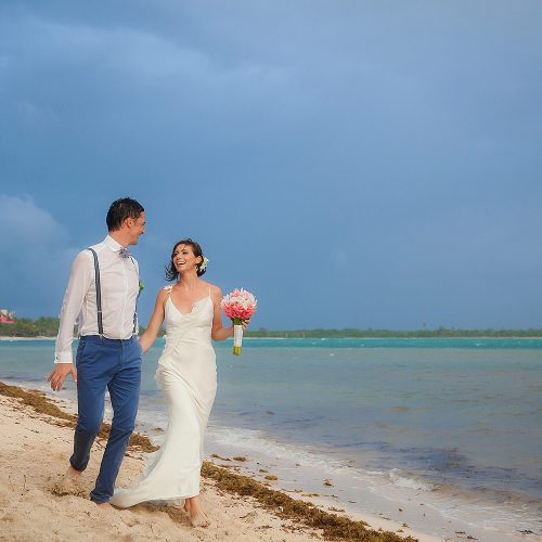 Bride and groom walking on beach in Tulum