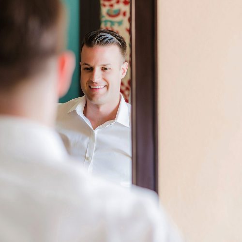 Groom looking in mirror getting ready at NOW Jade Riviera Cancun wedding