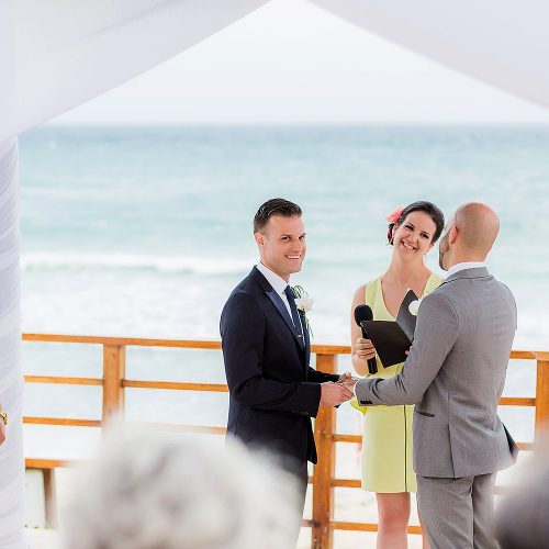 Groom putting on rings at gay wedding.