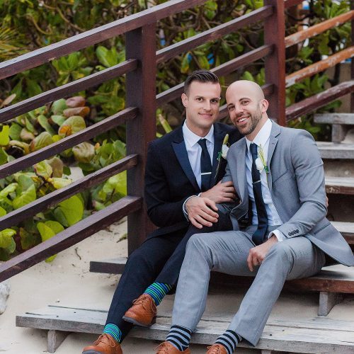 Grooms siting on steps at gay wedding at NOW Jade Riviera Cancun, Mexico