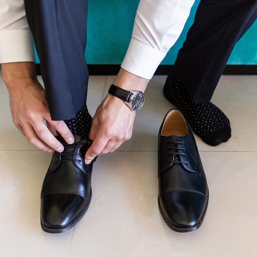 Close up of the groom putting on shoes at NOW Jade resort Cancun