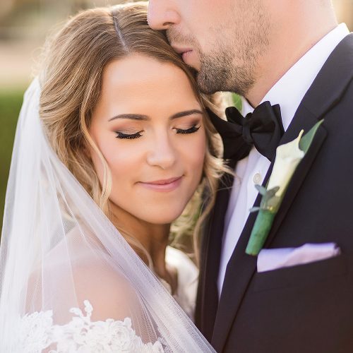 Groom kissing bride on forehead after wedding.