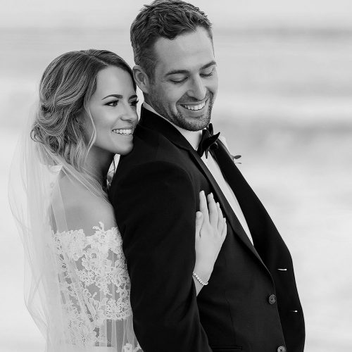 Bride hugging groom from behind on beach at wedding in Cancun | Dean Sanderson Weddings