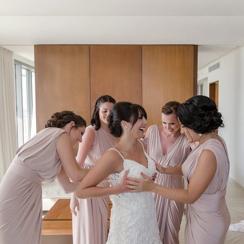 Bride getting dress on with bridesmaids.