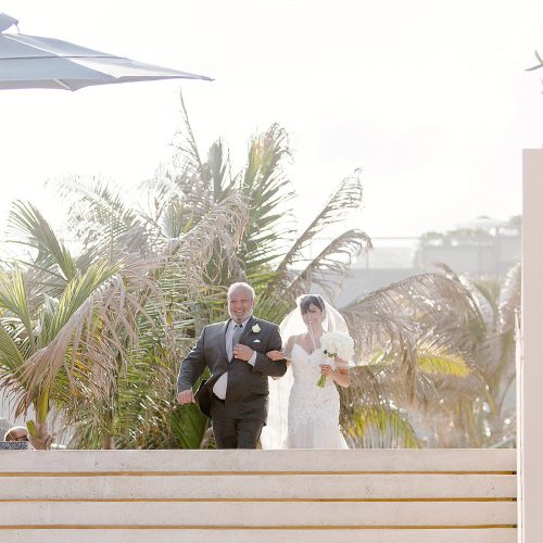 Bride walking to wedding ceremony on beach at Secrets on the vine Cancun