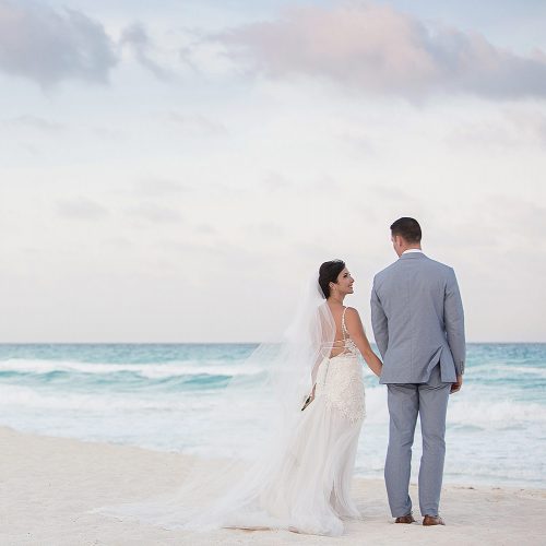Bride and groom looking away on beach in Cancun