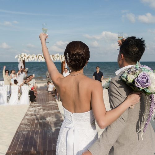 Bride and groom saluting guests at wedding ceremony on beach in Cancun