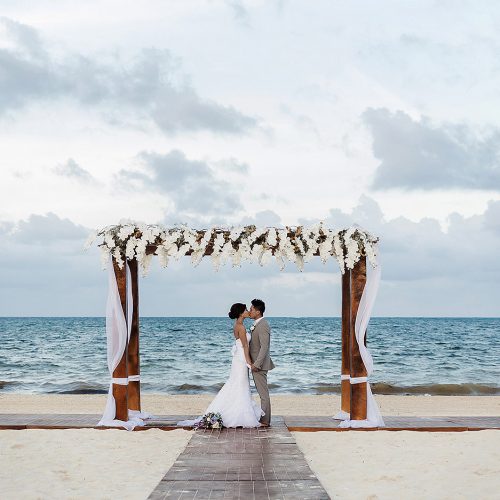 Bride and groom under alter at Moon Palace Cancun beach ceremony