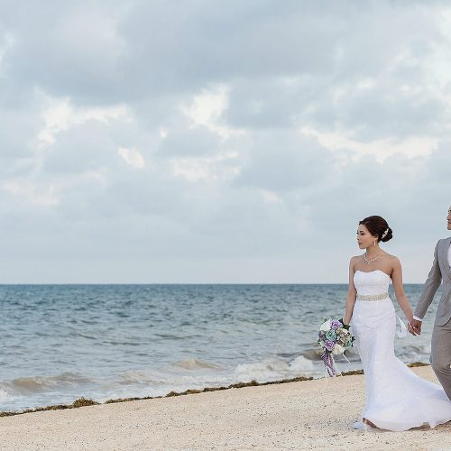 Bride and groom walking and holding hands on beach in Cancun