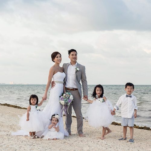 Bride and groom with flower girls and ring bearer on beach in Cancn