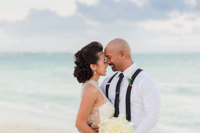 Bride and groom facing each other on beach in Cancun at sunset