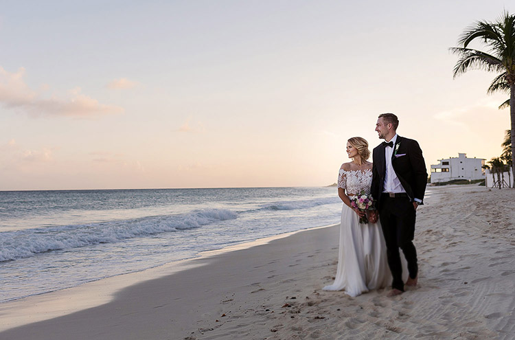 Bride and groom walking on beach in Cancun at sunset