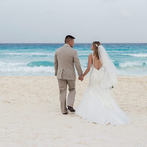 Bride and groom walking on beach in Cancun