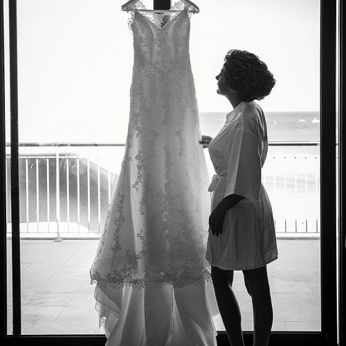 Bride standing at window looking at wedding dress in Playa del Carmen