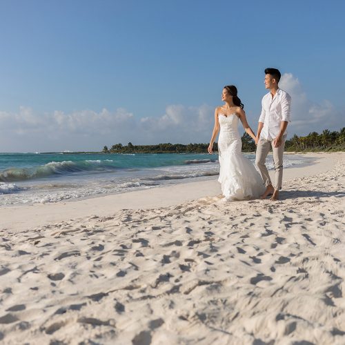 Bride and groom walking and holding hands on beach in Riviera Maya Mexico