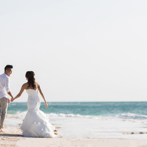 Bride and groom walking by the water on beach in Riveira Maya Mexico