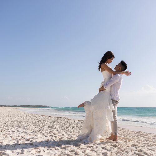Bride on top of groom on beach in Riveira Maya Mexico