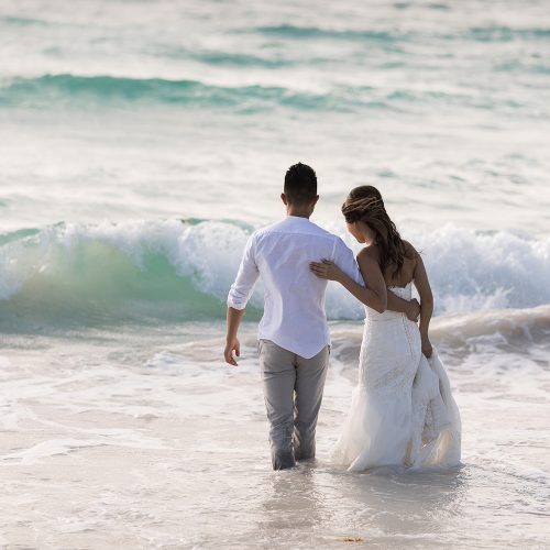 Bride and groom walking into water at TTD on beach in Riveira Maya Mexico