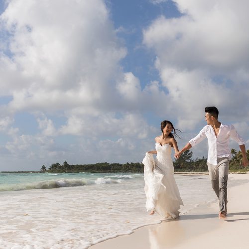 Bride and groom running after walk on beach.