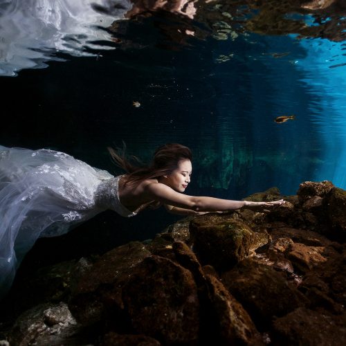 Bride swimming forwards in Cenote Trash the Dress (TTD) in Mexico