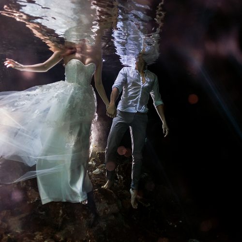 Bride and groom holding hands underwater Cenote Trash the Dress (TTD) in Mexico