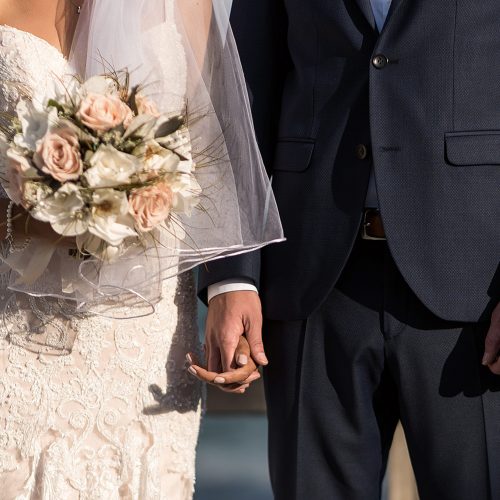 Close up of bride and groom holding hands at wedding