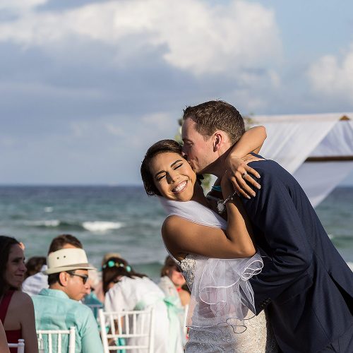 Groom kissing bride laughing at Punta Venado, Riviera Maya Mexico