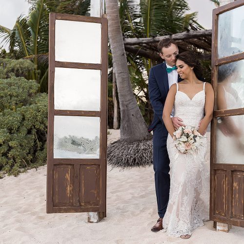Bride and groom beside old doors at punta venado beach club