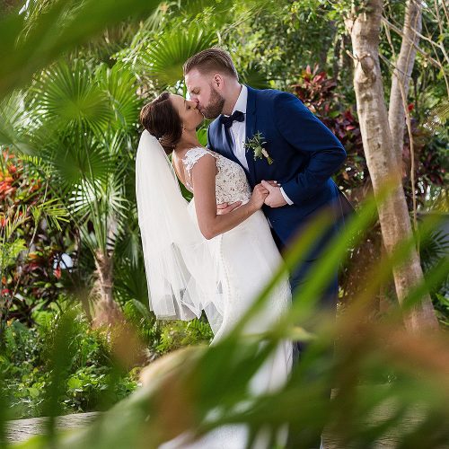 Bride and groom kissing in garden at Azul Fives Riviera Maya