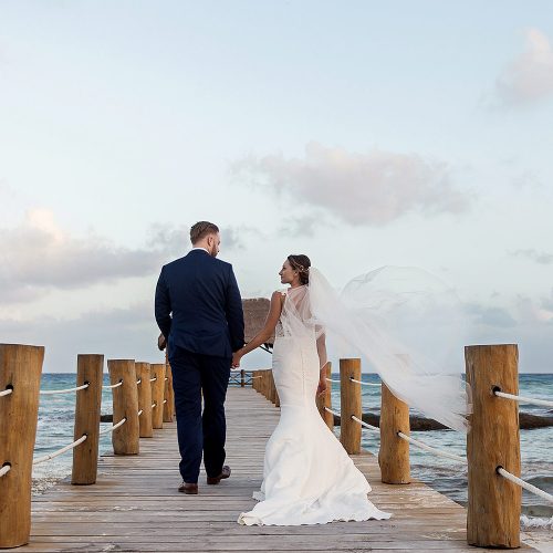 Bride and groom walking on dock at Azul Fives Riviera Maya