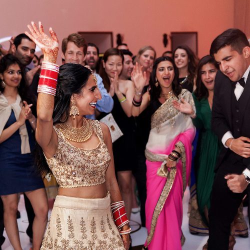 Bride dancing with guests at Indian wedding reception.