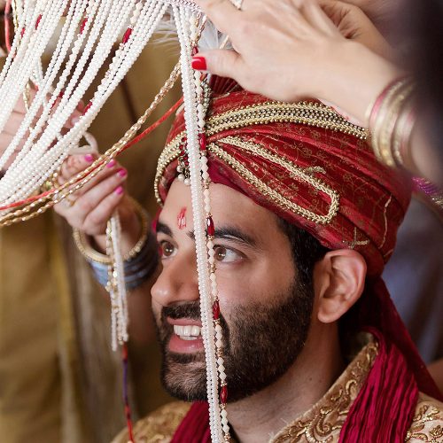 Groom having head dress put on at sikh wedding
