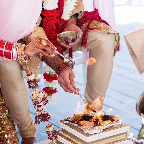 Groom putting oil on fire during Indian wedding ceremony.