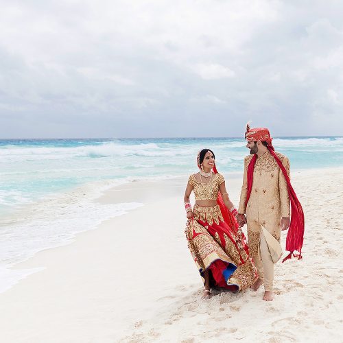 Indian bride and groom walking on beach in Cancun