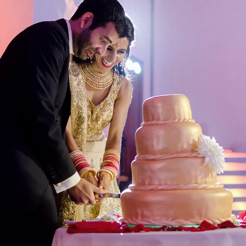 Bride and groom cutting the cake at Indian wedding reception.