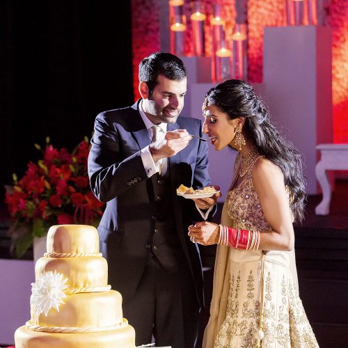 Bride and groom cutting the cake at Indian wedding reception.